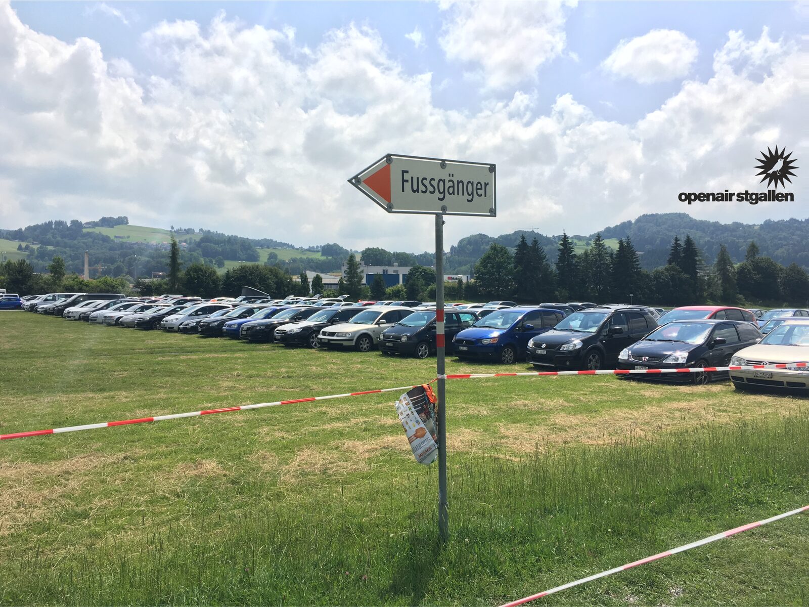 Bewegwijzering voor voetgangers bij een evenementenparkeerterrein in het gras.